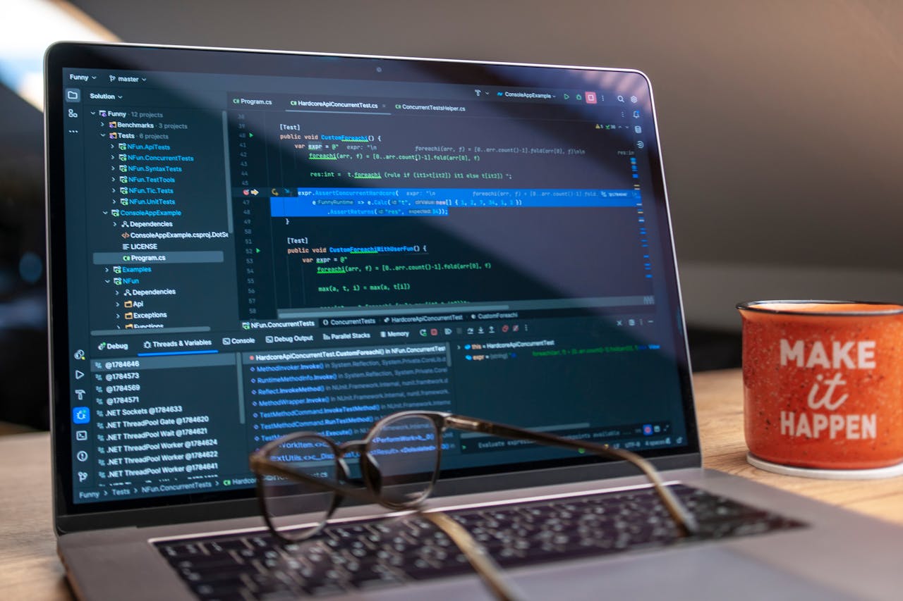 services-02 A laptop displaying code editor with a motivational mug that reads 'Make It Happen' on a workspace.